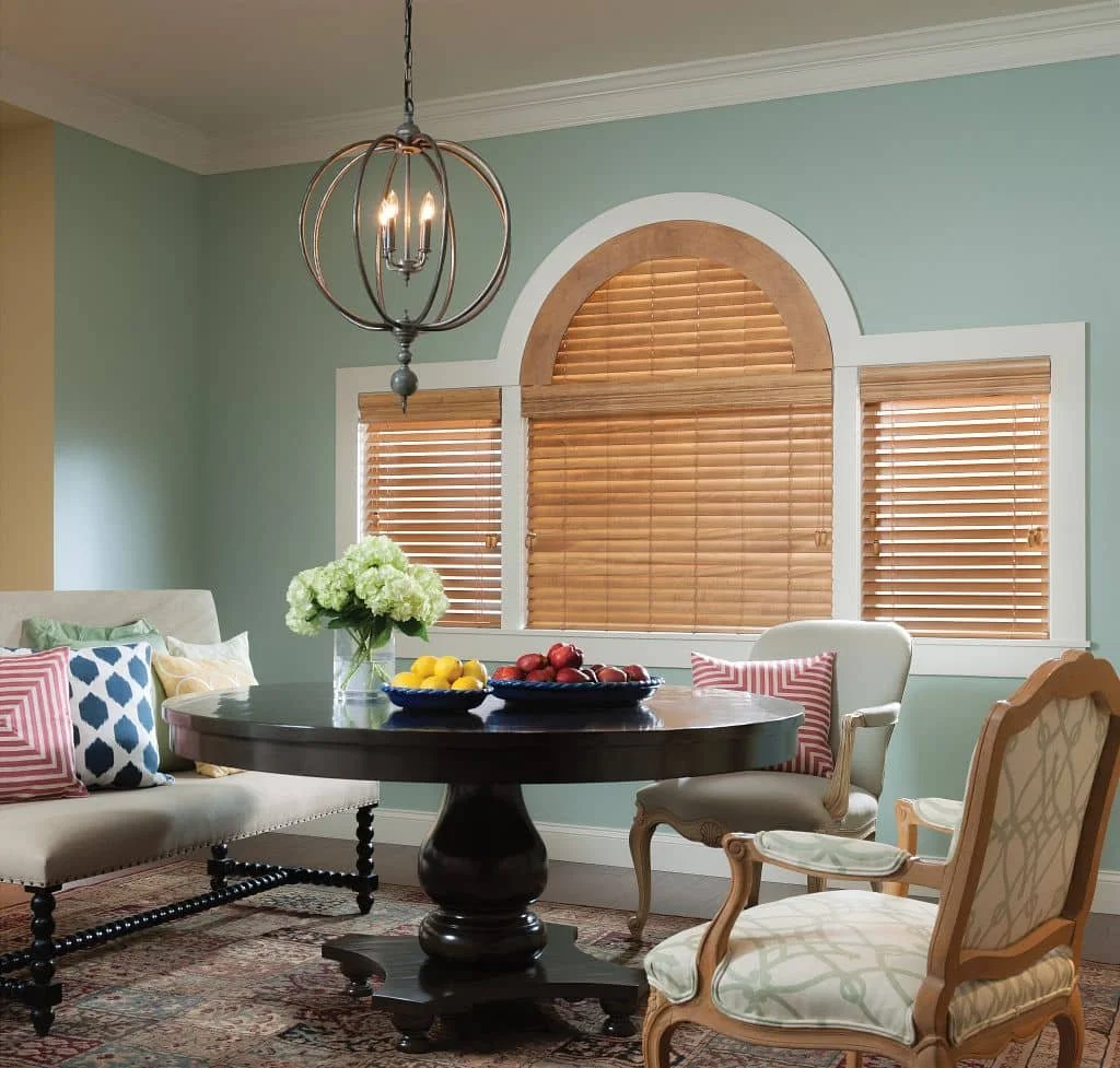 Custom blinds for odd shaped windows with arched wood blinds in an elegant dining room
